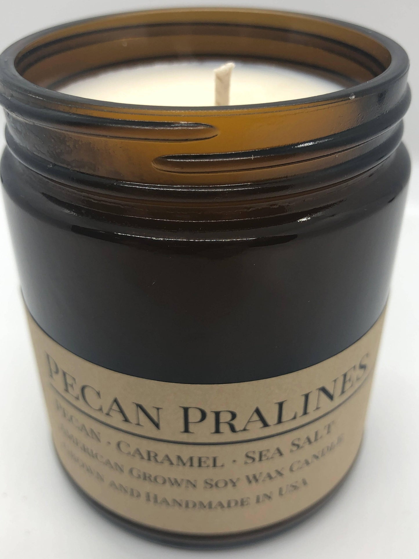 Pecan Pralines soy wax candle in a 9 oz amber apothecary jar from Prairie Fire Tallow with lavender accents.