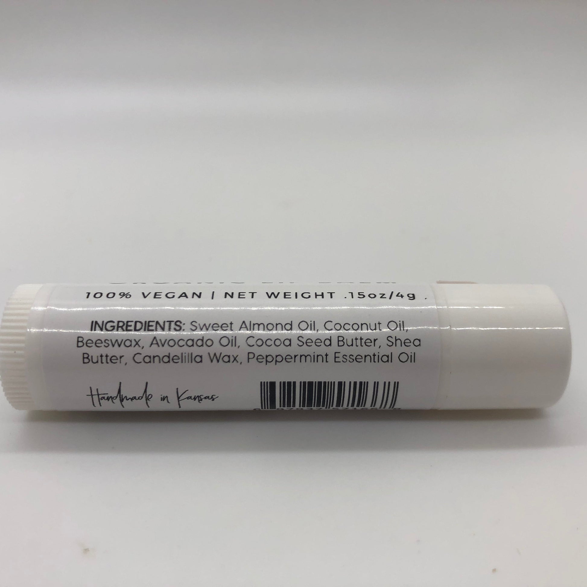 Peppermint lip balm stick from Prairie Fire Tallow with a white tube and mint leaves in the background.