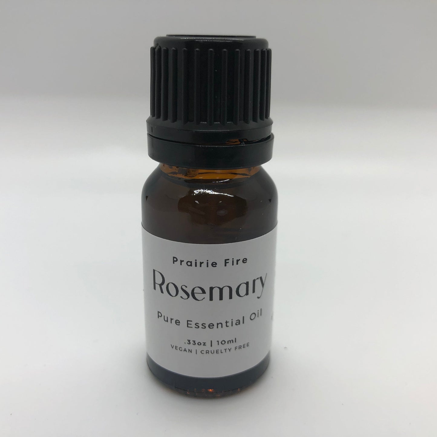 Bottle of Prairie Fire Rosemary Essential Oil in a 10 ml (0.35 oz) dark glass bottle with a white cap.