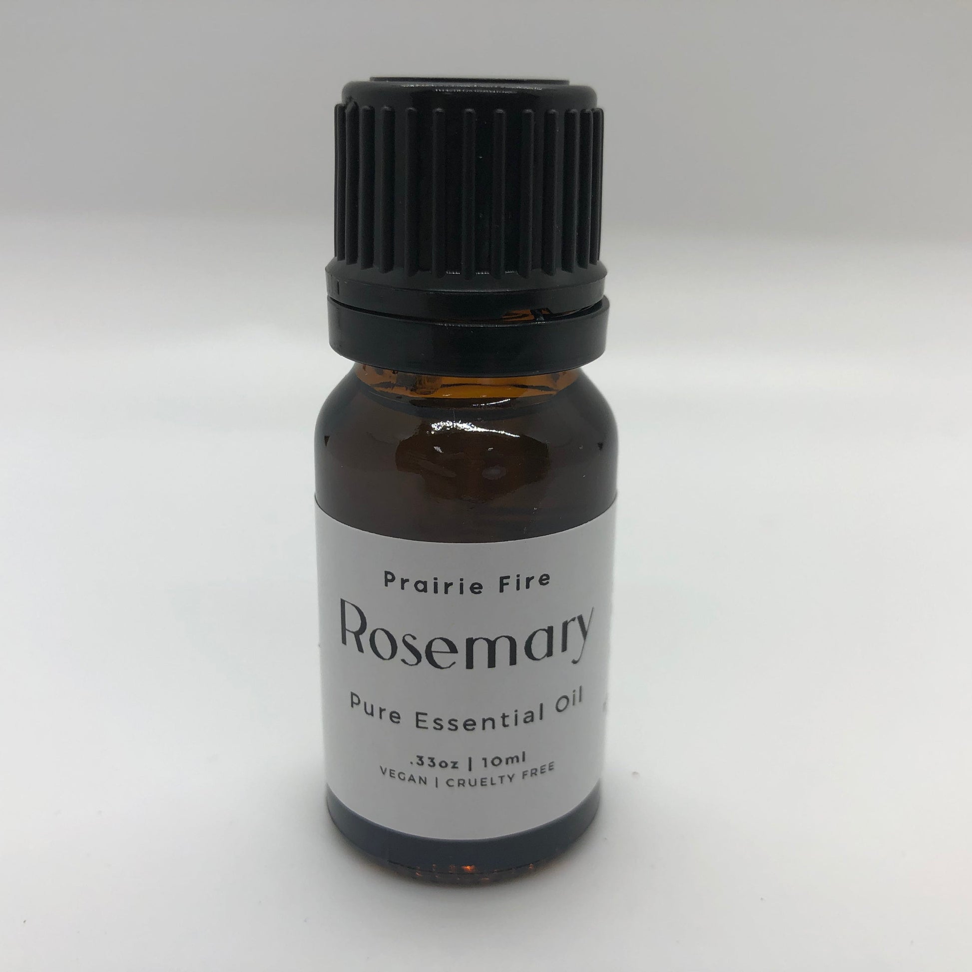 Bottle of Prairie Fire Rosemary Essential Oil in a 10 ml (0.35 oz) dark glass bottle with a white cap.