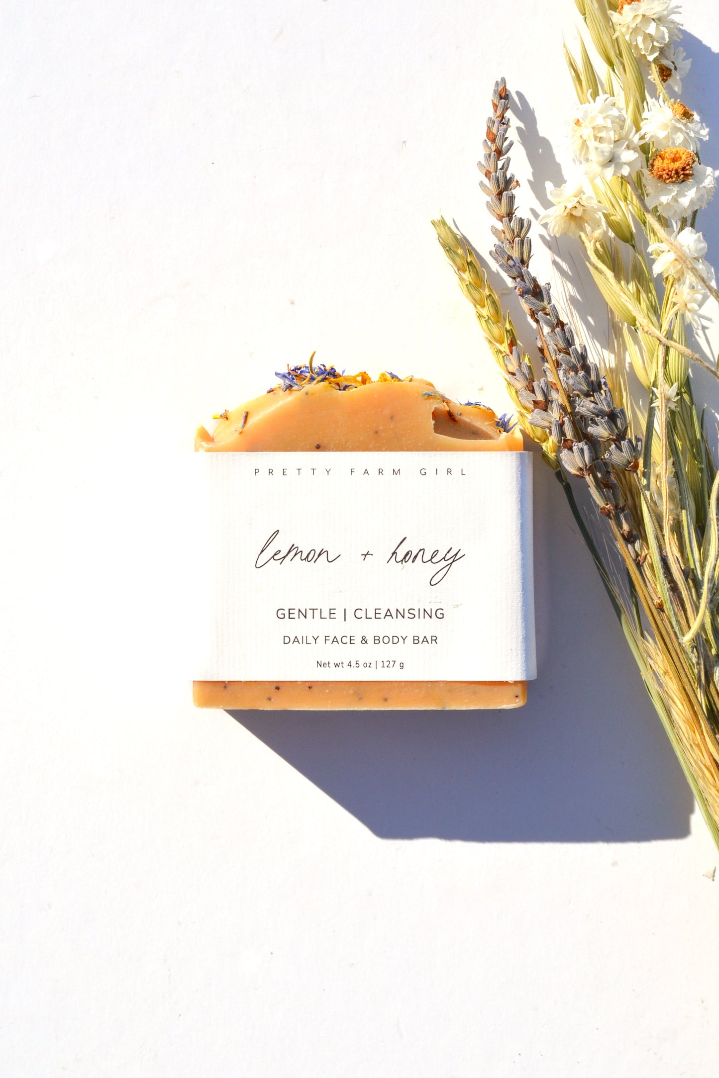 Handmade lemon, honey, and poppy seed tallow and goat milk soap bar by Pretty Farm Girl, showing natural ingredients and textured surface.
