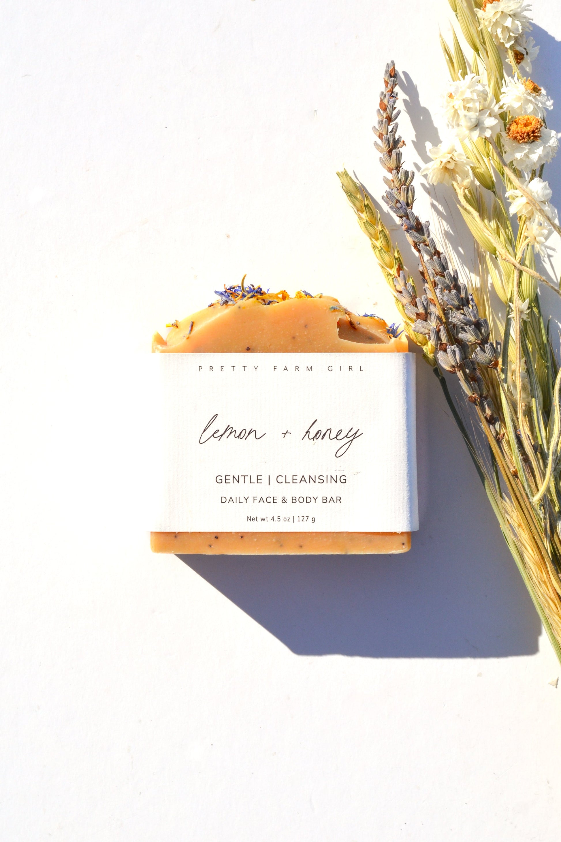 Handmade lemon, honey, and poppy seed tallow and goat milk soap bar by Pretty Farm Girl, showing natural ingredients and textured surface.