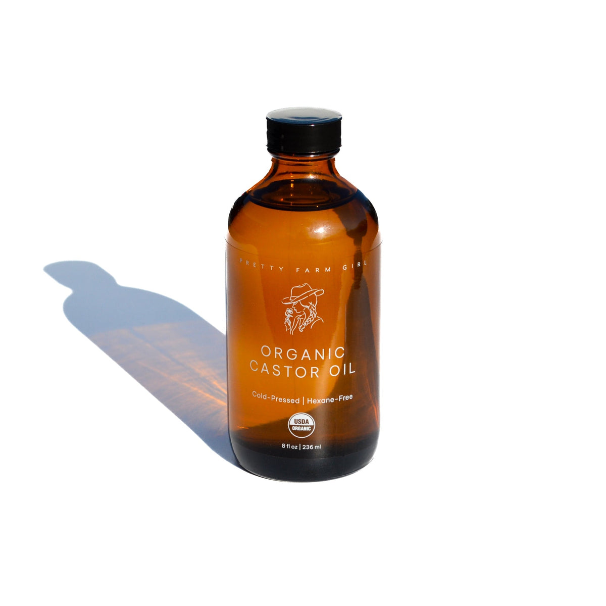 Pretty Farm Girl organic cold pressed castor oil in a clear bottle, showing the golden liquid inside.