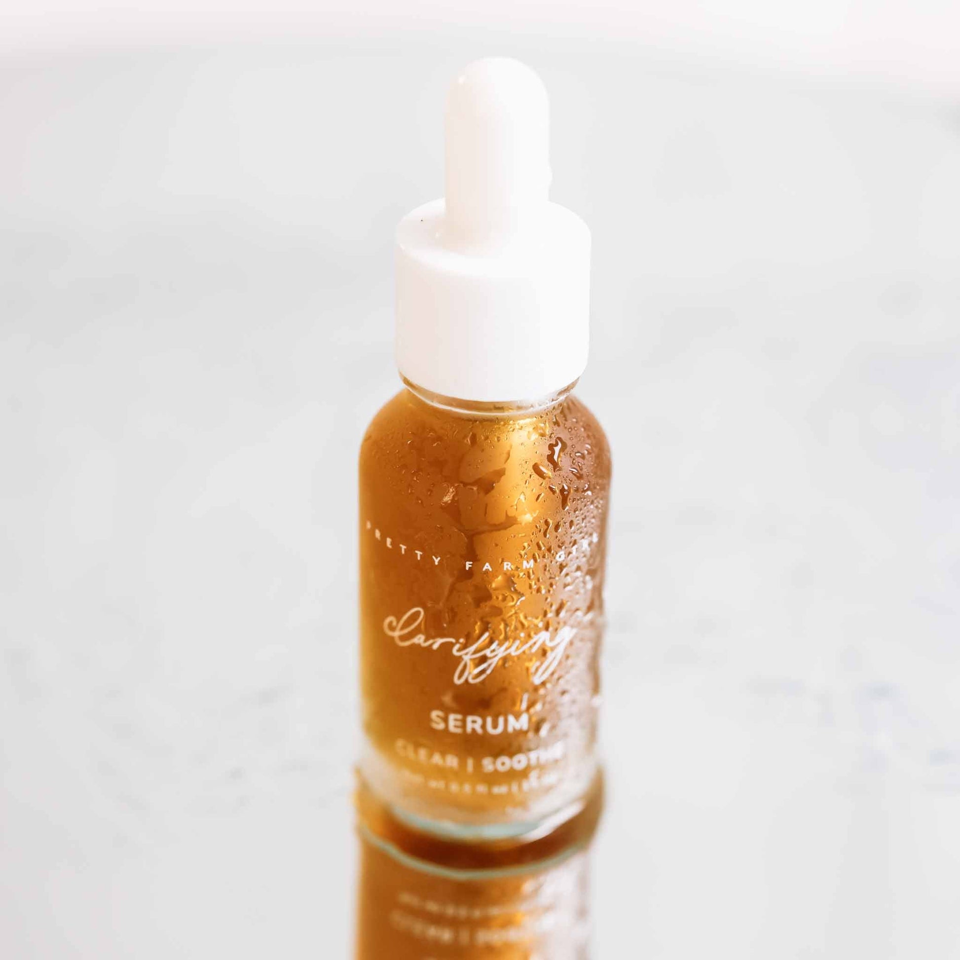 Bottle of Pretty Farm Girl clarifying face serum for acne-prone skin with dropper applicator on a neutral background.