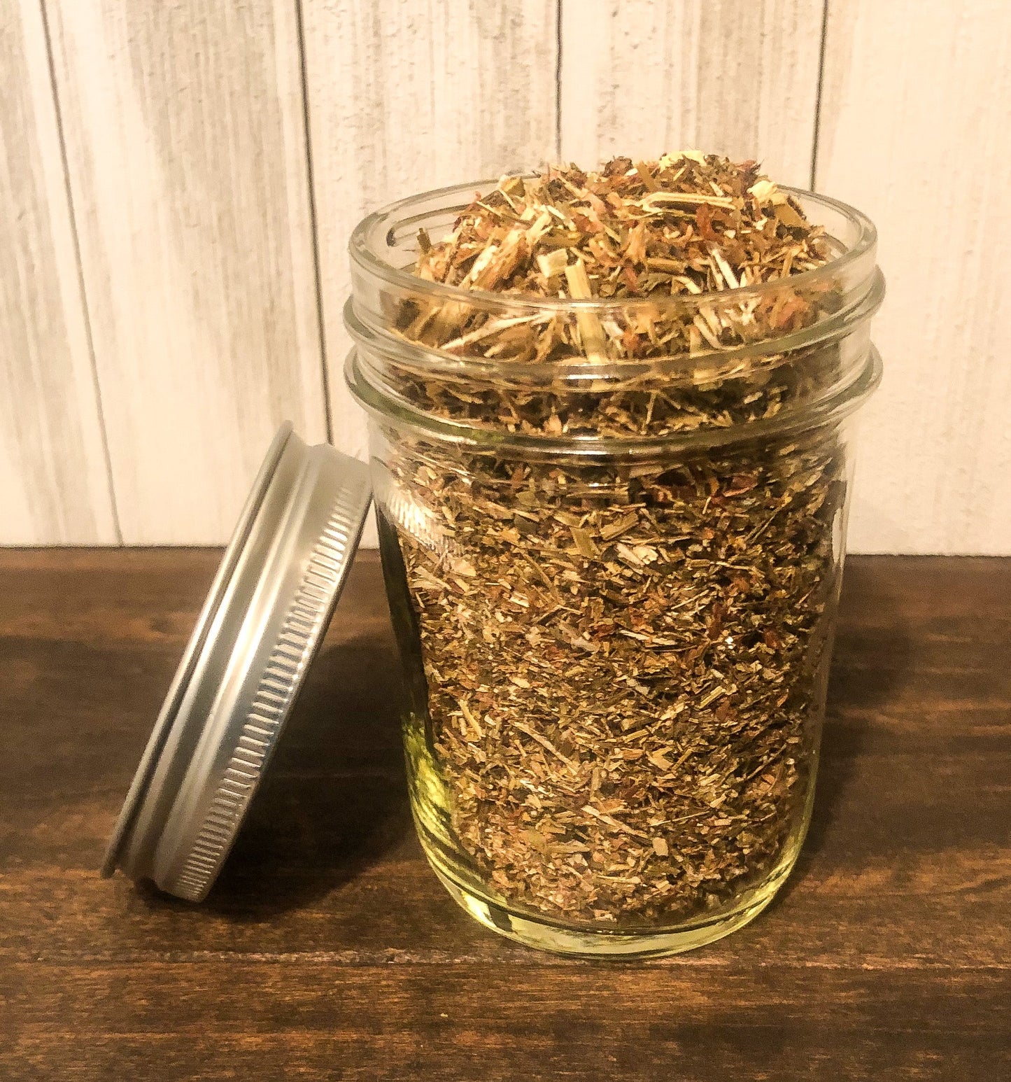 Small jar of dried red clover herbs in herbalroseapothecary herb jars, showcasing the herbs' vibrant color and packaging.
