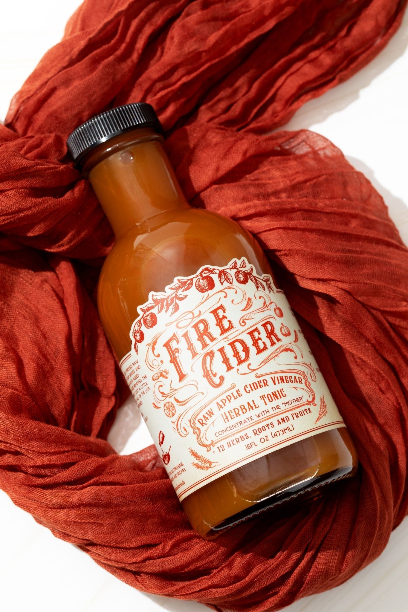 16 oz bottle of Fire Cider by Roots and Leaves LLC, featuring a label with fiery ingredients and natural herbal remedy visuals.