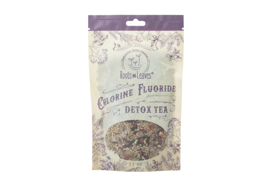 Roots and Leaves LLC Chlorine and Fluoride Detox Tea in a clear glass mug with tea leaves and lemon slices.