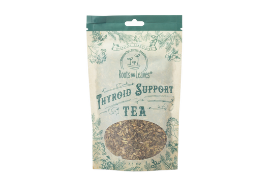 Herbal thyroid support tea in a clear glass cup with tea leaves, promoting natural wellness by Roots and Leaves LLC.