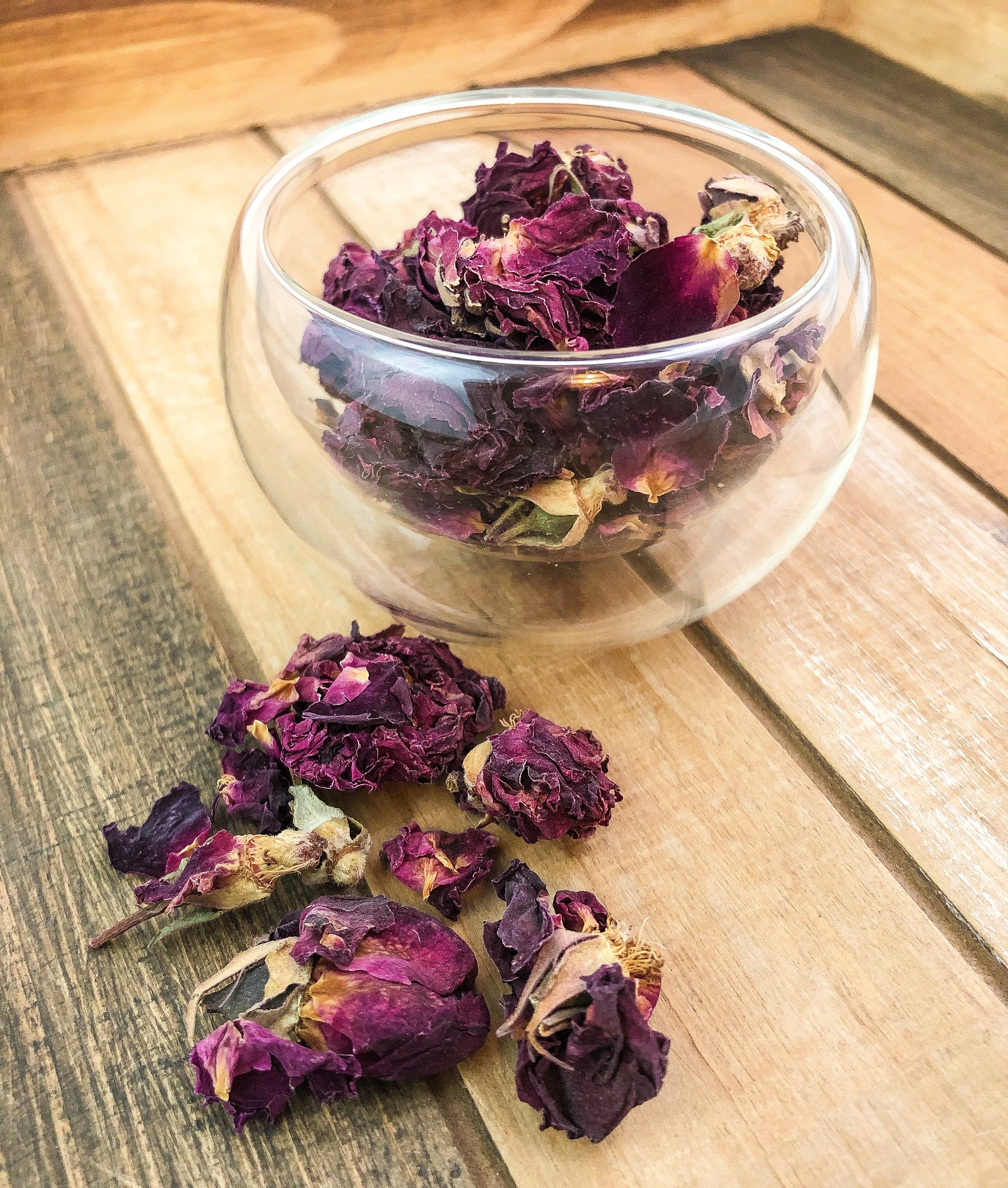 Fresh pink rose petals from Herbal Rose Apothecary, arranged in a delicate pile on a white background.