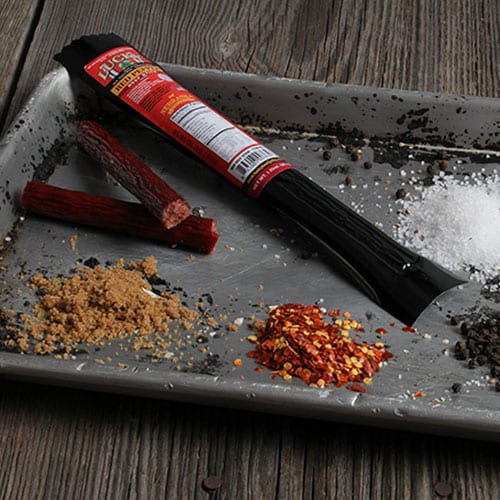 Red Pepper Beef Stick from Nebraska Star Beef, a 1.25 oz spicy snack with red pepper seasoning, displayed on a wooden surface.