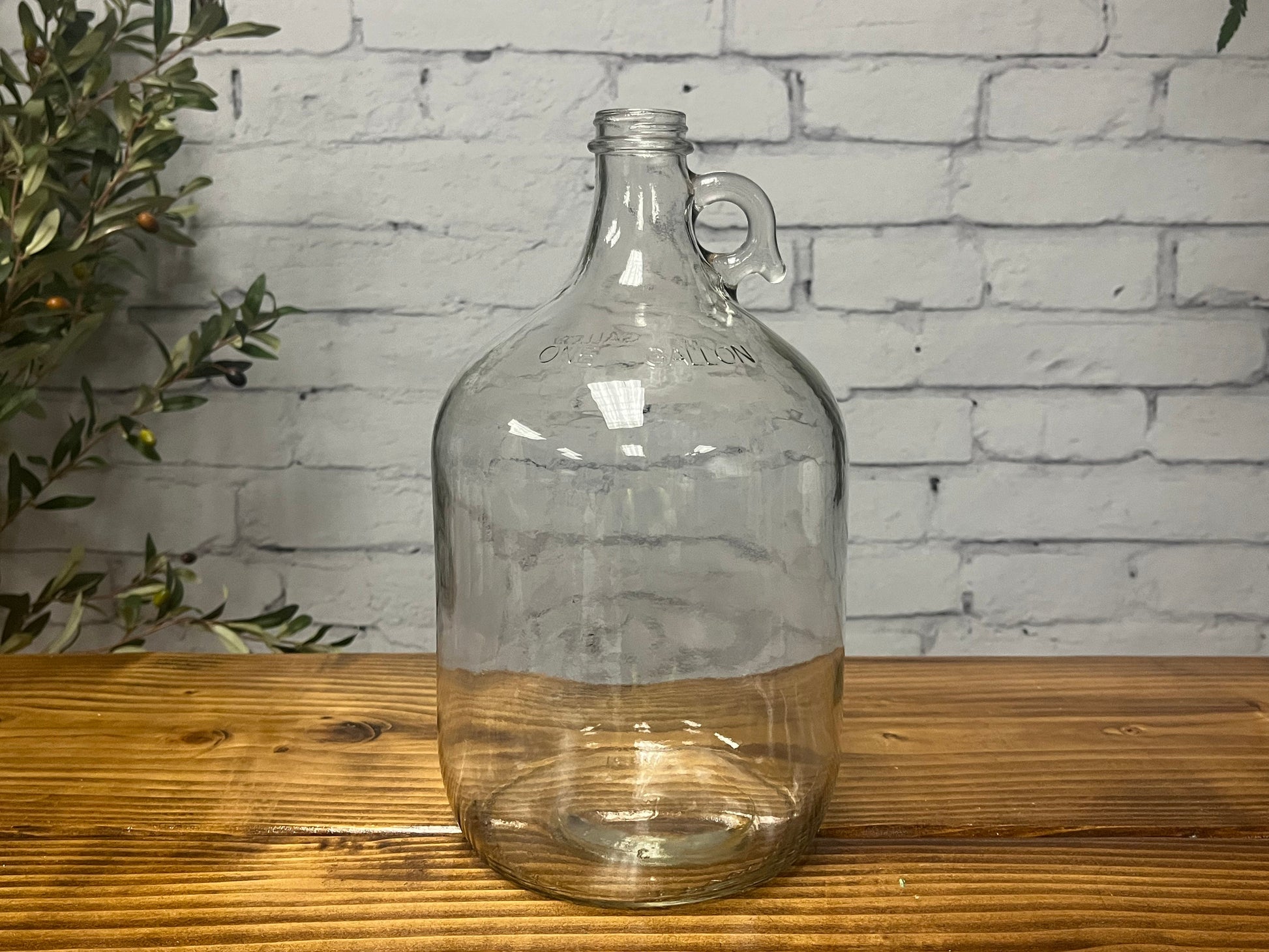 1-gallon glass jug with cap by Rustic Strength, featuring a clear glass body and secure lid for liquids storage.