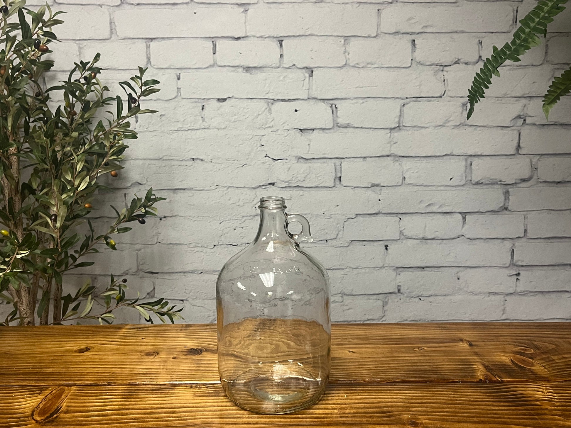 1-gallon glass jug with cap by Rustic Strength, transparent container for liquids, with a secure lid.