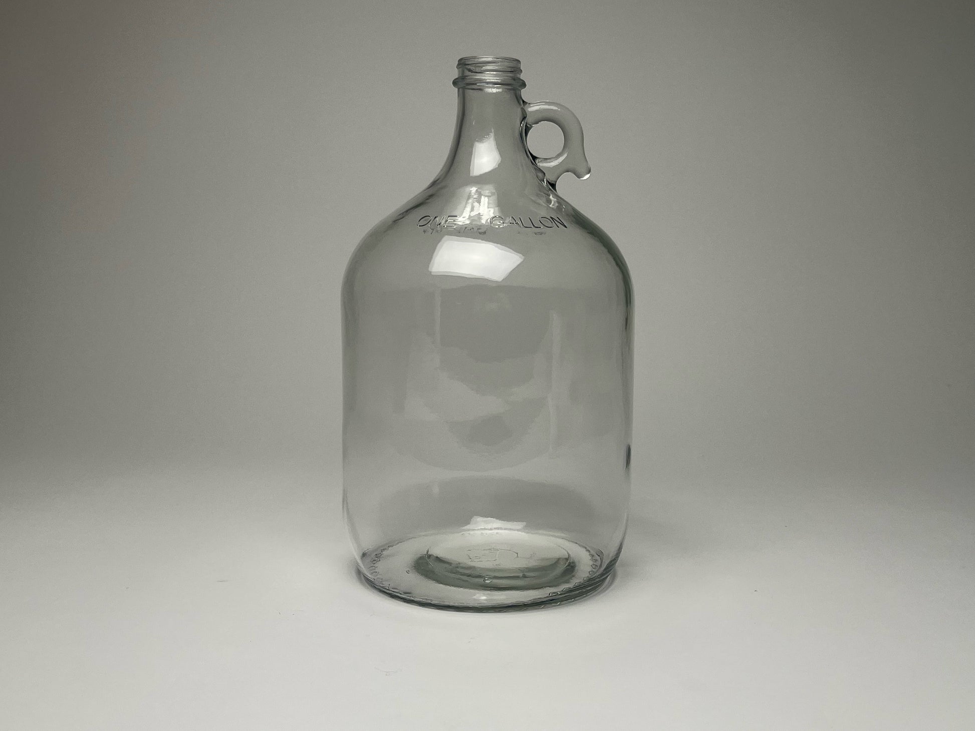 1-gallon glass jug with cap by Rustic Strength, showcasing its clear glass body and secure lid for liquid storage.