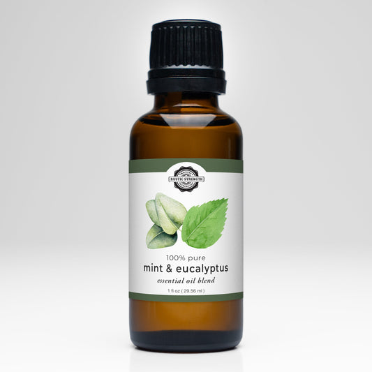 Rustic Strength Mint and Eucalyptus Essential Oil Blend scent bottle with a natural label and fresh mint and eucalyptus leaves.