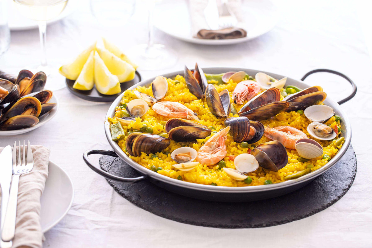 Premium Saffron Threads from Vanilla Bean Kings sprinkled over a seafood paella dish, showcasing vibrant orange-red saffron strands.