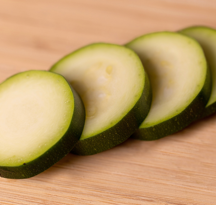 Packet of Spineless Supreme Hybrid Zucchini Seeds by Seeds 'n Such, showing 10-12 seeds in a clear seed packet.