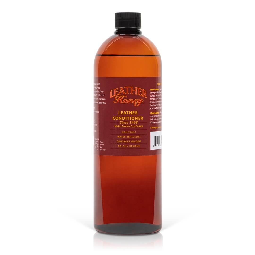 Leather Honey leather conditioner bottle, clear label, and applicator brush on a clean surface, showcasing the product's packaging.
