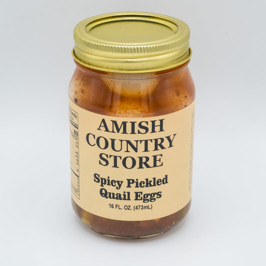Canned spicy pickled quail eggs from Amish Country Store with red chili peppers and spices in a glass jar.