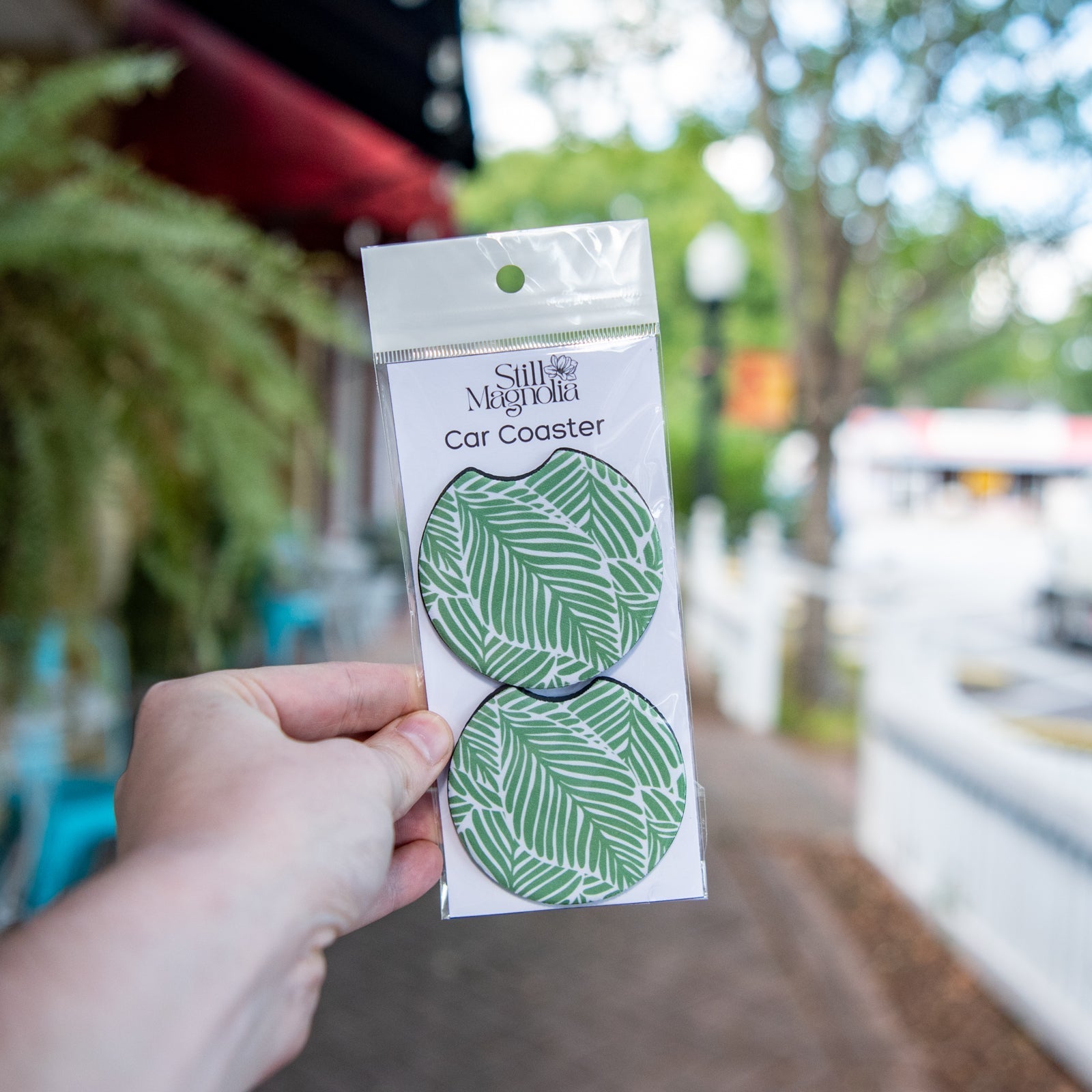 Still Magnolia Leafy Luxe car coaster with leafy green design, made of absorbent material for vehicle cup holders.