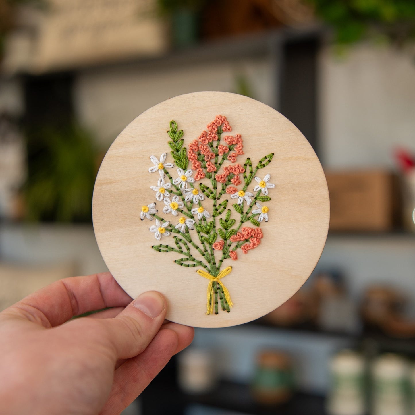 Still Magnolia Daisy Bouquet embroidery kit featuring colorful fabric and embroidery supplies for creating a floral design.