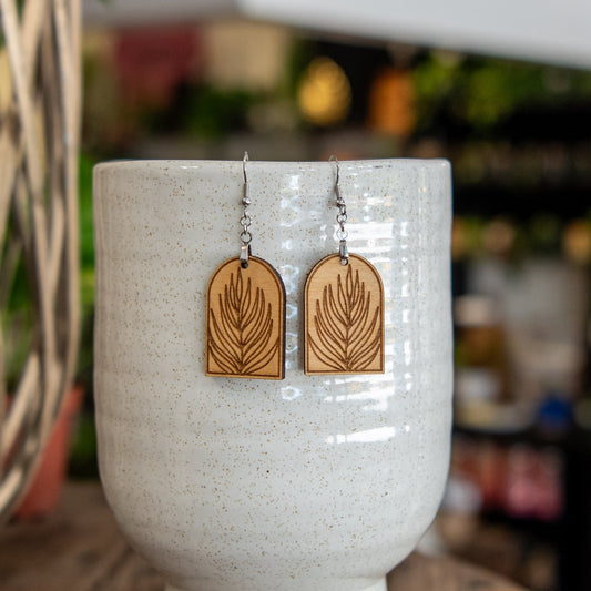 Still Magnolia palm leaf arched earrings featuring gold-tone metal with leaf-shaped design and elegant curved style.