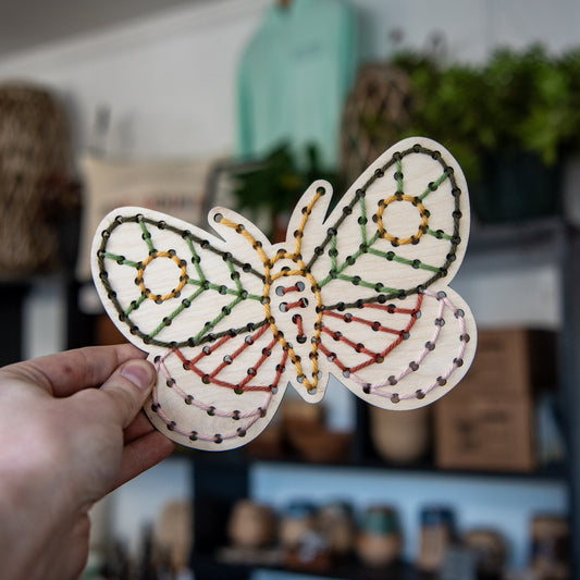 Still Magnolia Moth Yarn Embroidery Kit featuring colorful yarns, embroidery hoops, and fabric for crafting decorative textile art.