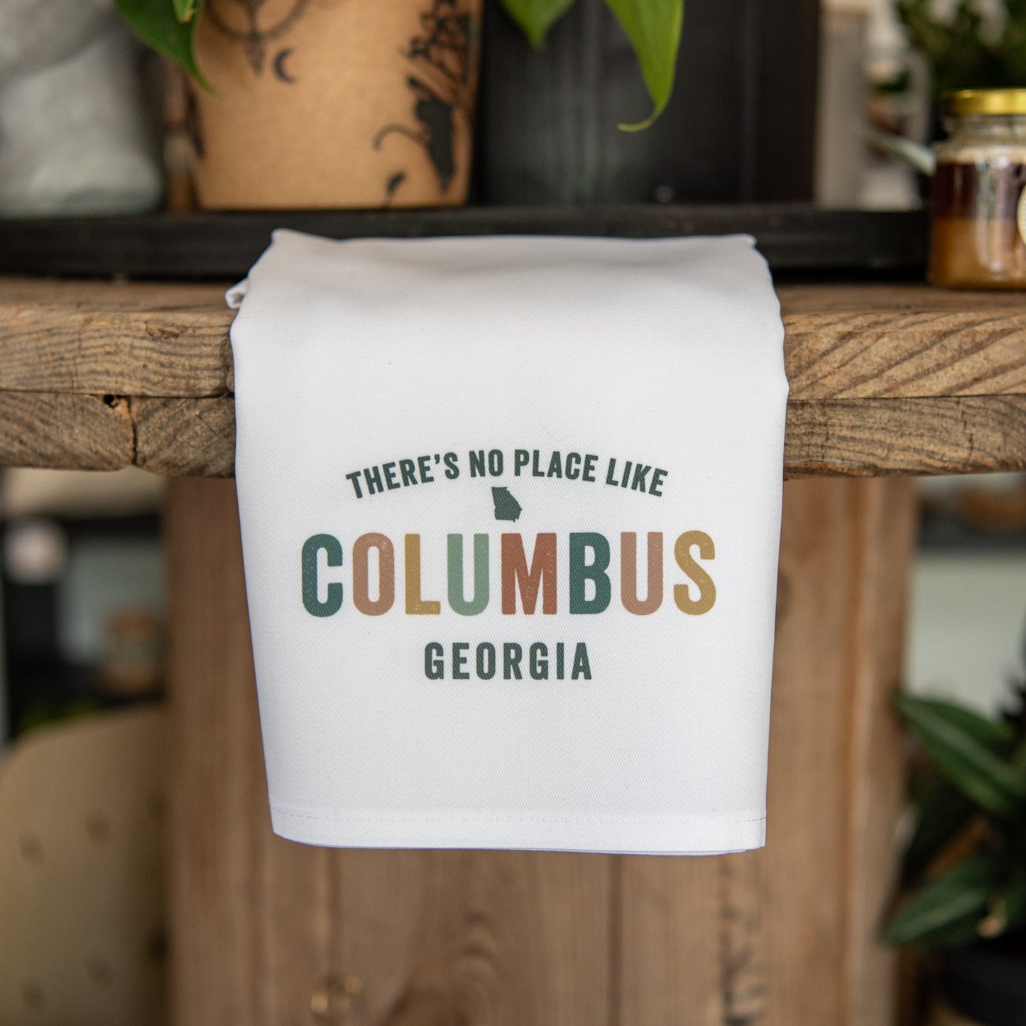 Personalized Still Magnolia tea towel featuring custom city design with the phrase "There's No Place Like [Your City]" on a decorative fabric.