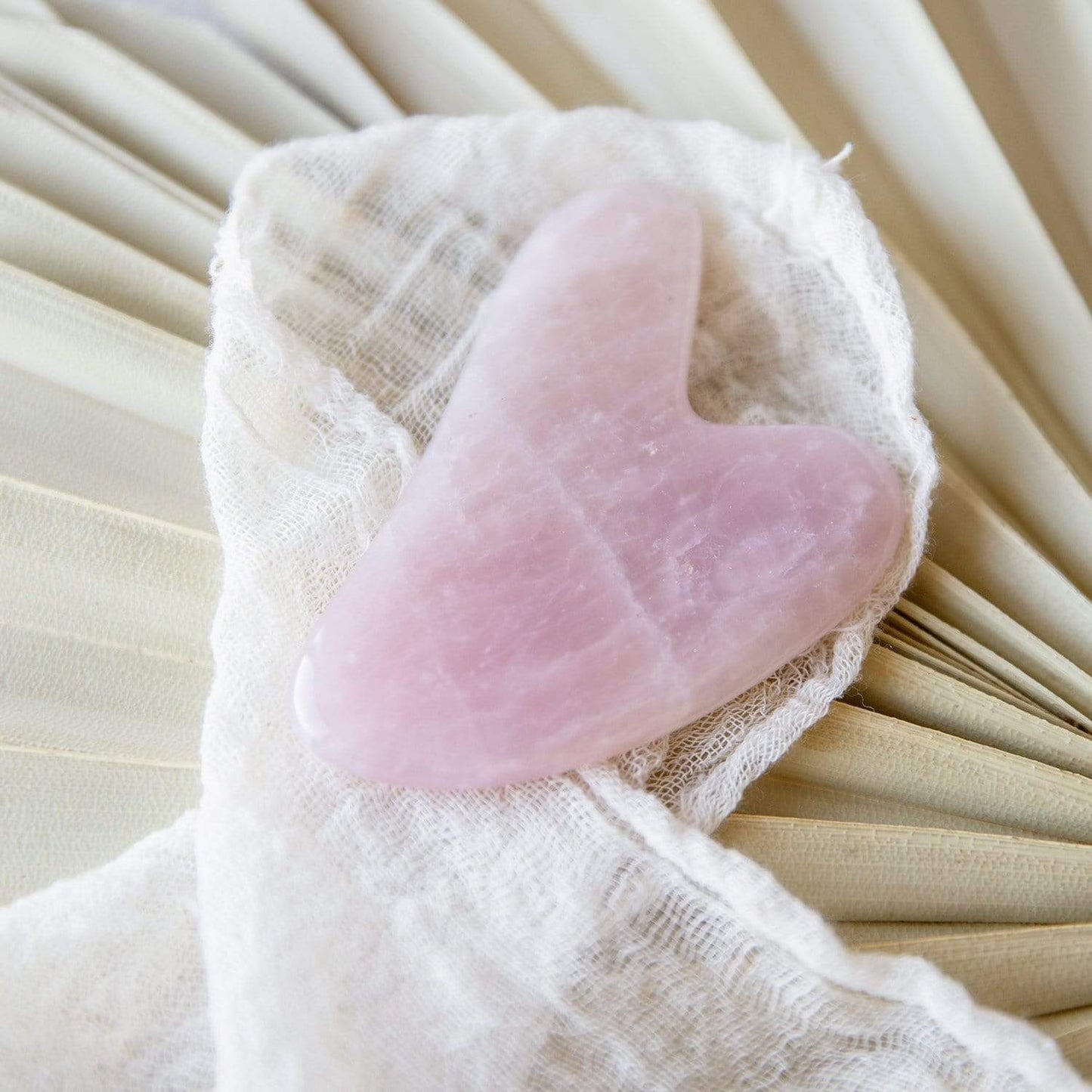 Rose quartz Gua Sha facial tool for skin care, with a smooth, curved design for facial massage and skin rejuvenation.
