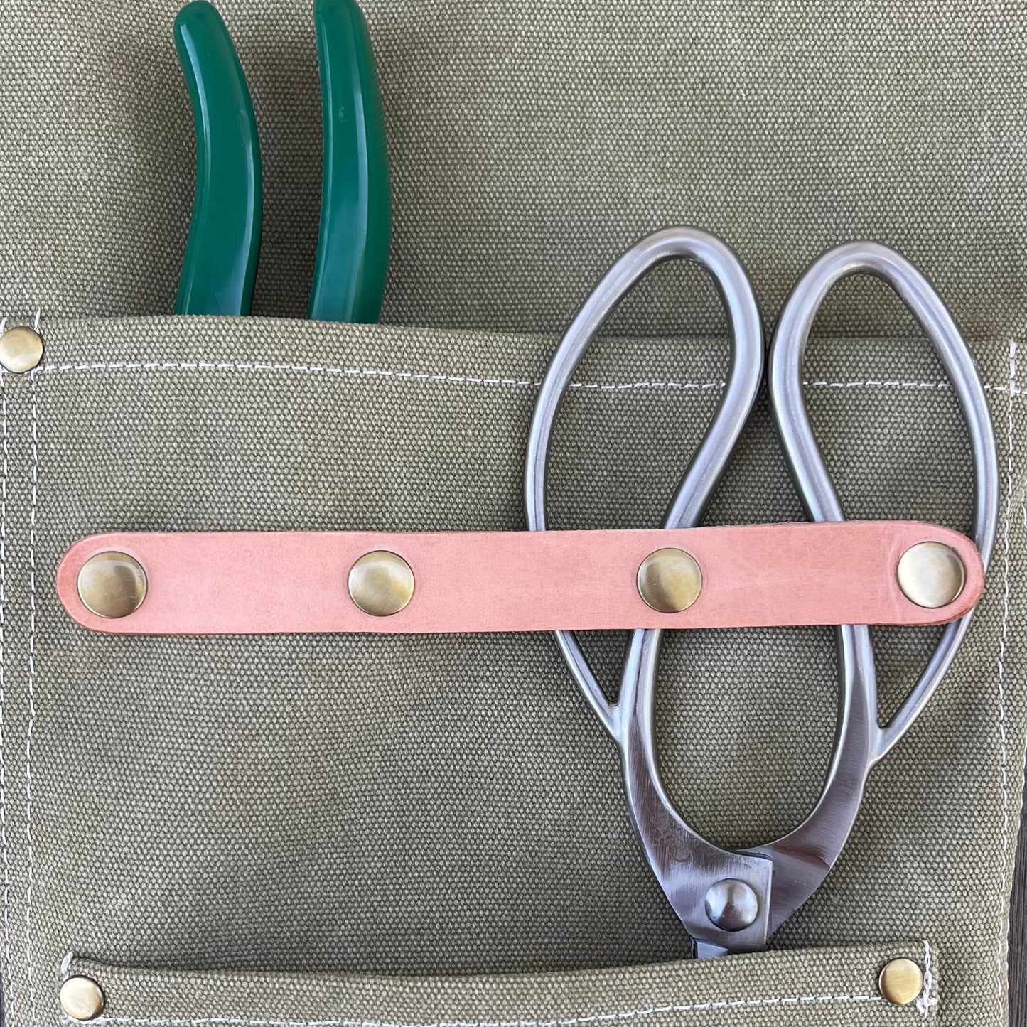 Dark green waxed canvas gardening apron by The Celtic Farm with multiple pockets for tools and gardening essentials.