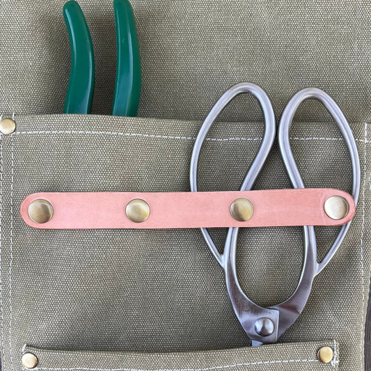 Dark green waxed canvas gardening apron by The Celtic Farm with multiple pockets for tools and gardening essentials.