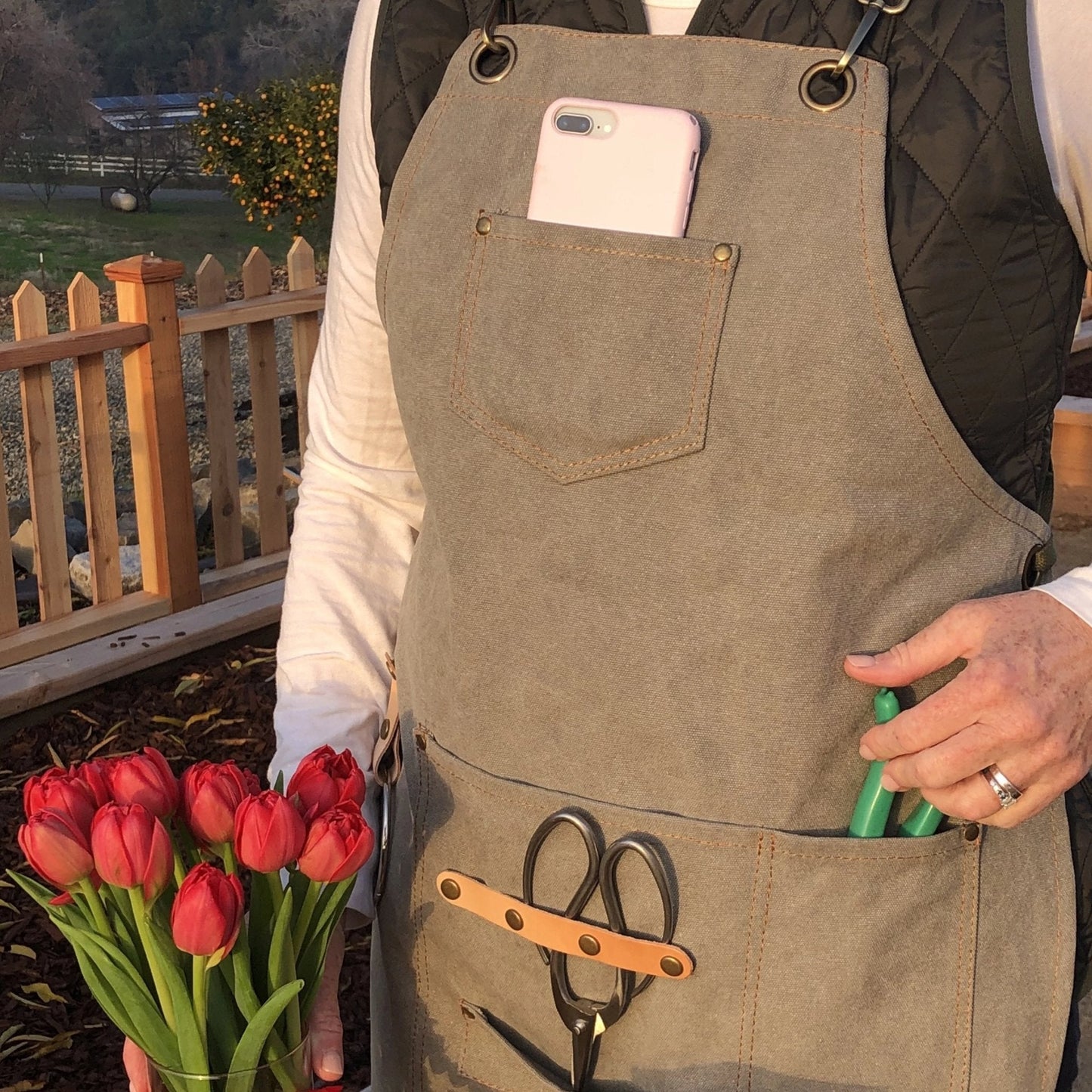 Dark green waxed canvas gardening apron with multiple pockets by The Celtic Farm, durable and practical for outdoor gardening tasks.