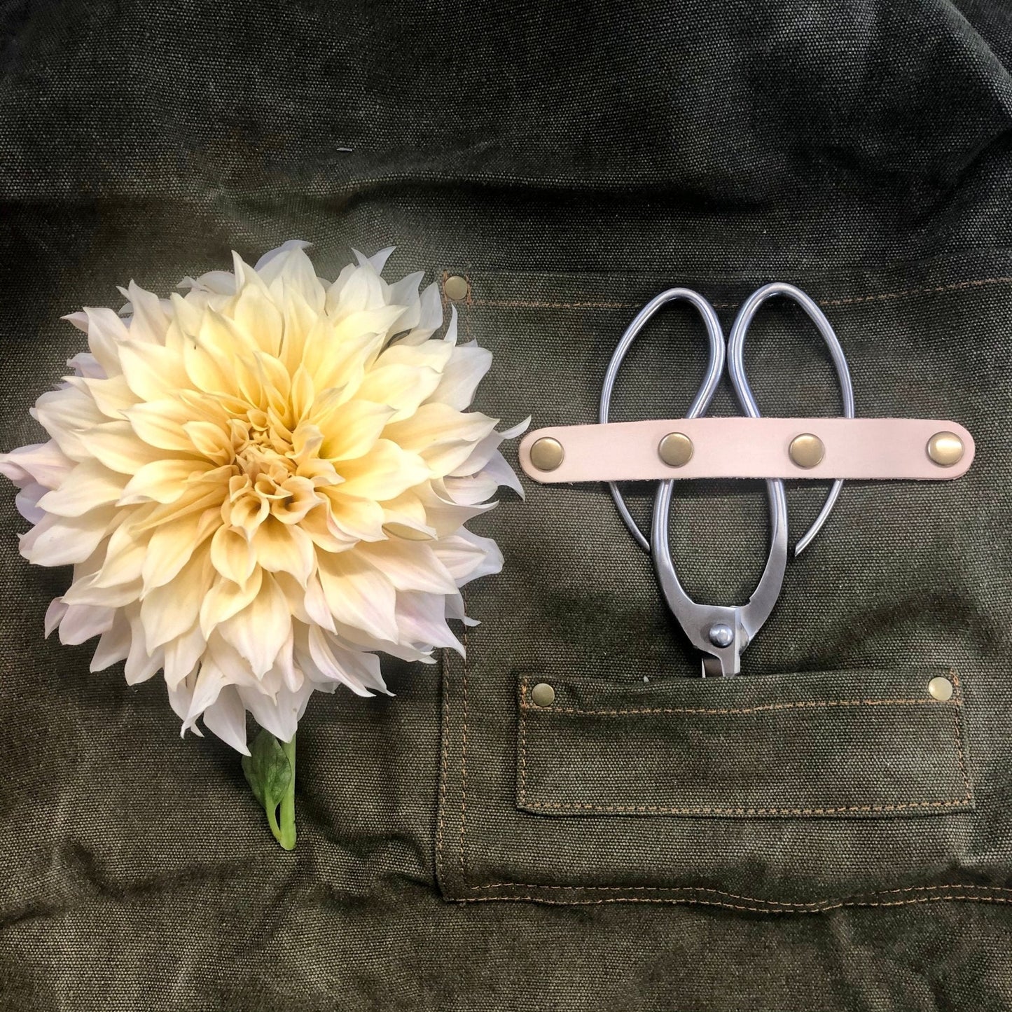 Dark green waxed canvas gardening apron with multiple pockets by The Celtic Farm, designed for gardening and outdoor tasks.