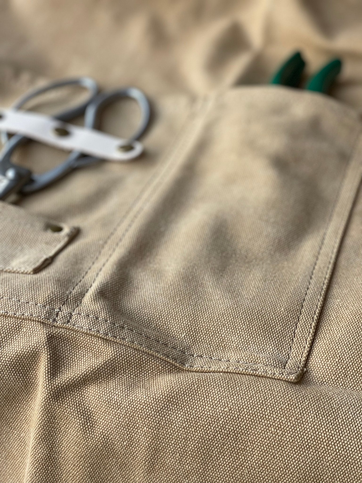 Dark green waxed canvas gardening apron with multiple pockets by The Celtic Farm, ideal for gardening and outdoor work.