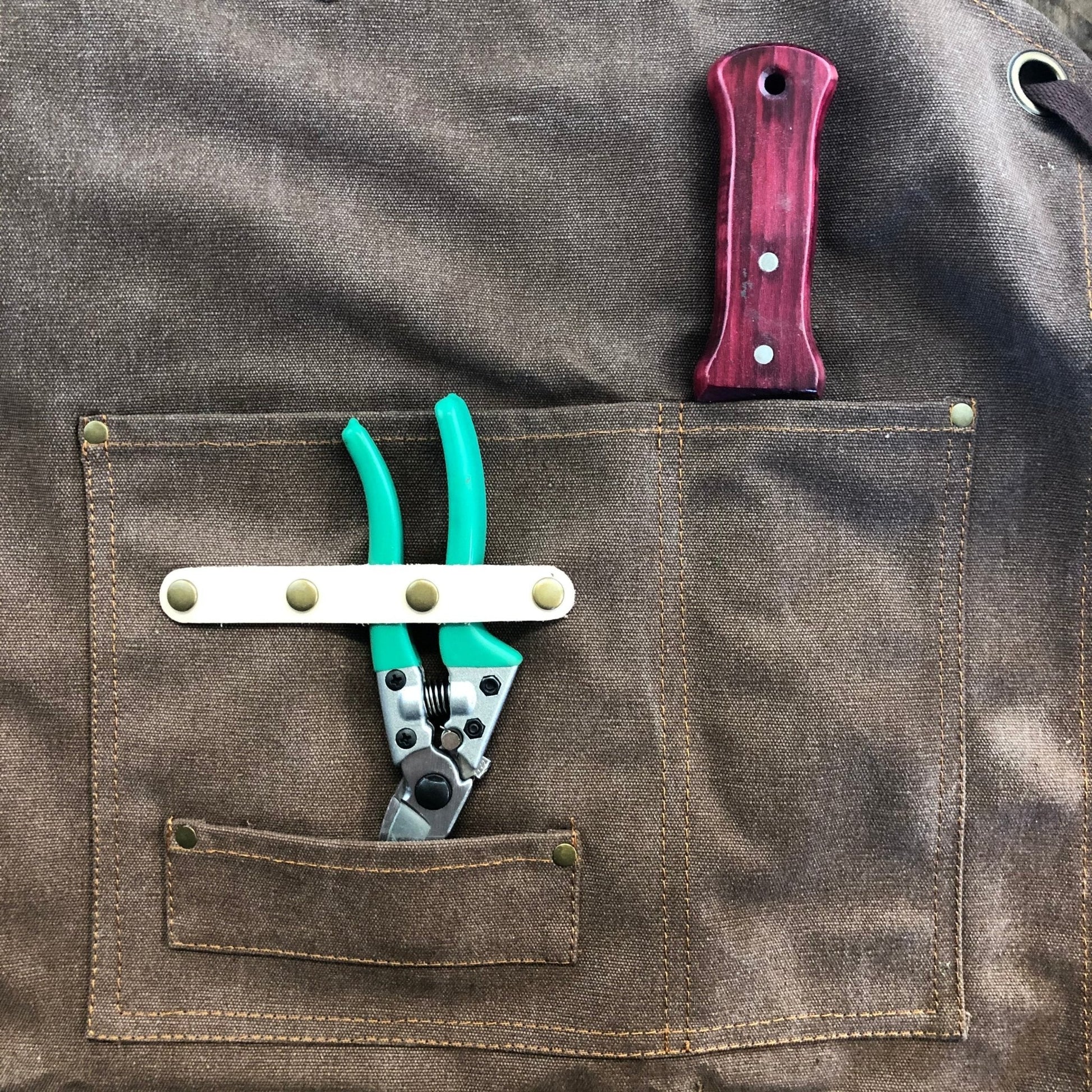 Dark green waxed canvas gardening apron with pockets by The Celtic Farm, durable apron for gardening and outdoor tasks.