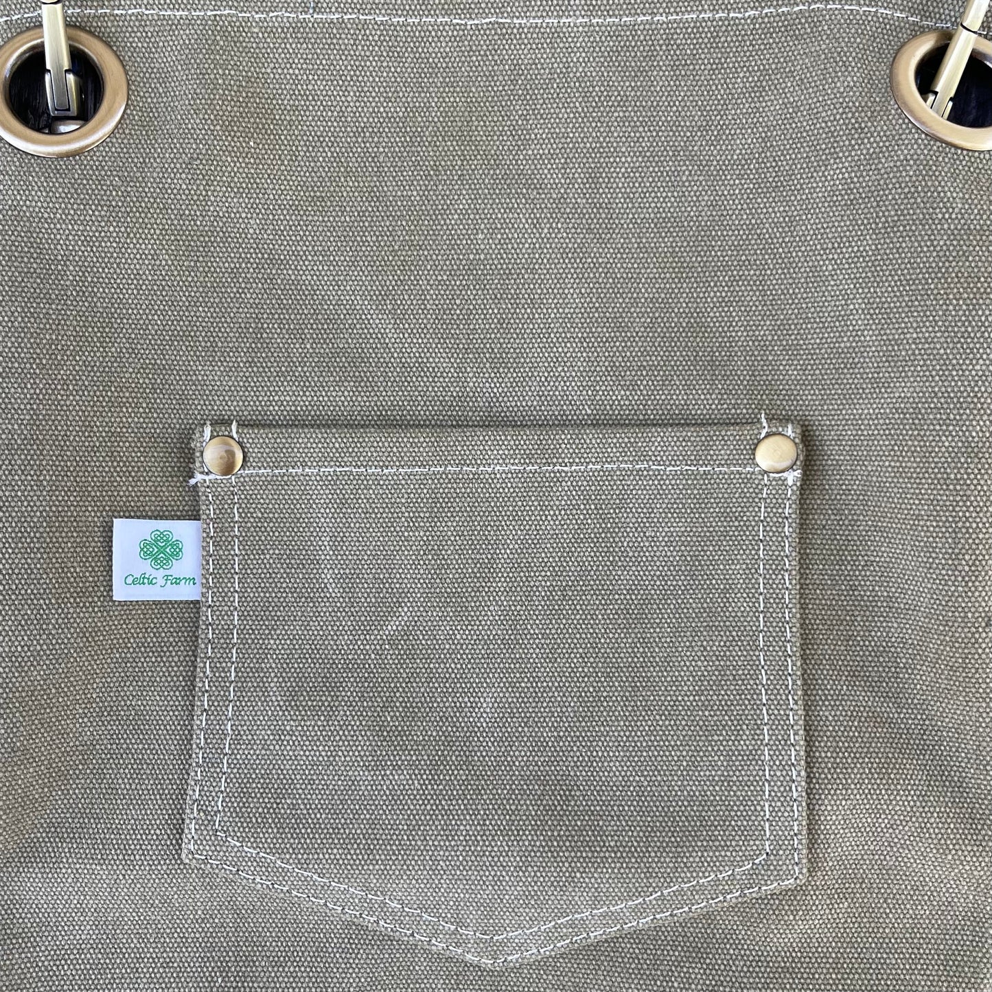 Dark green waxed canvas gardening apron with pockets from The Celtic Farm, durable apron ideal for gardening tasks.