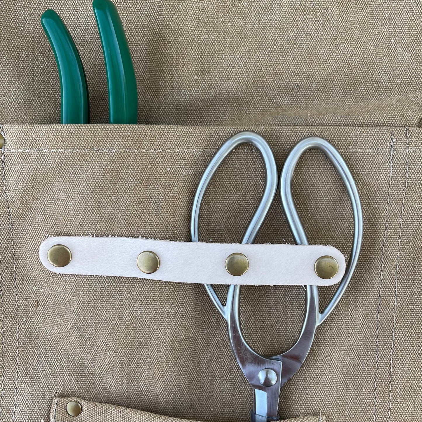 Dark green waxed canvas gardening apron with multiple pockets by The Celtic Farm, designed for outdoor gardening tasks.