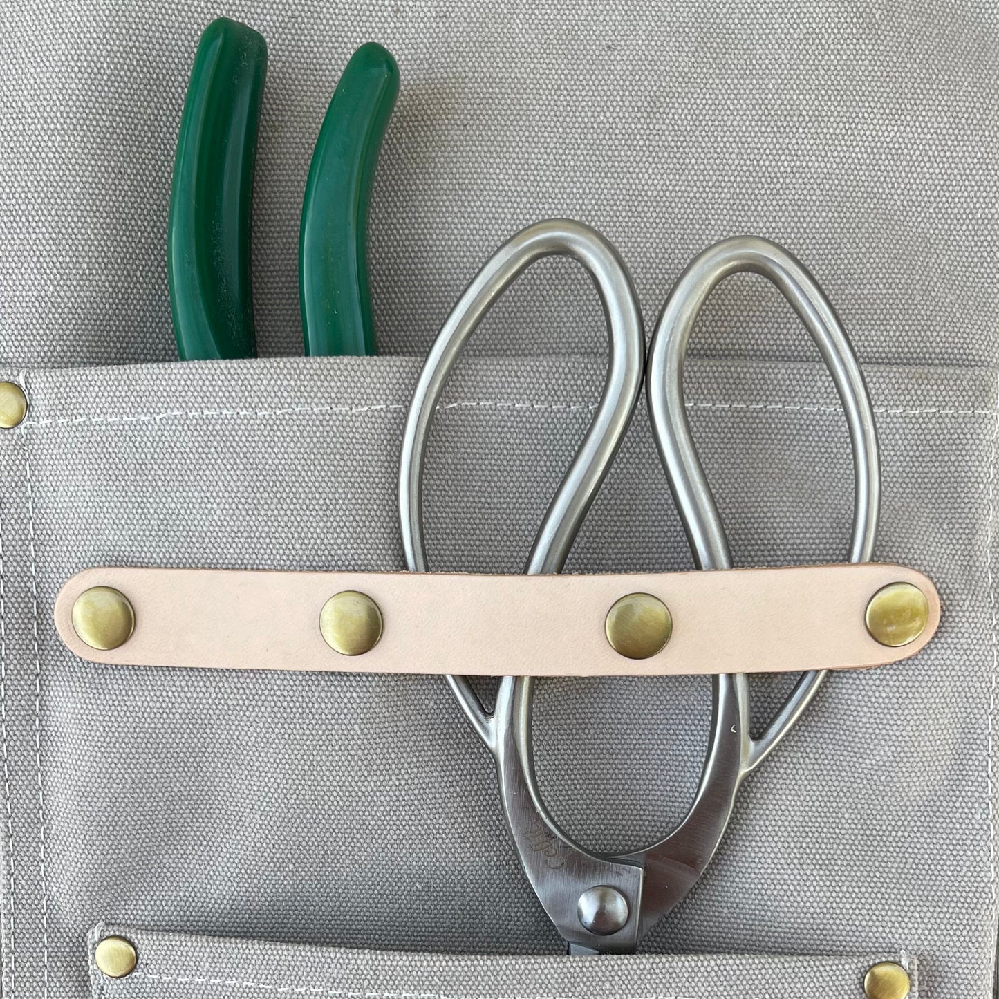 Dark green waxed canvas gardening apron with multiple pockets, designed by The Celtic Farm for outdoor gardening tasks.