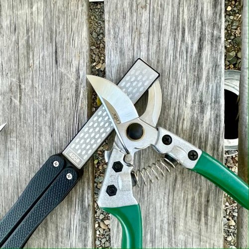 The Celtic Farm garden tool sharpener for clippers, with diamond and carbon steel honing surfaces, used for sharpening pruners and mower blades.