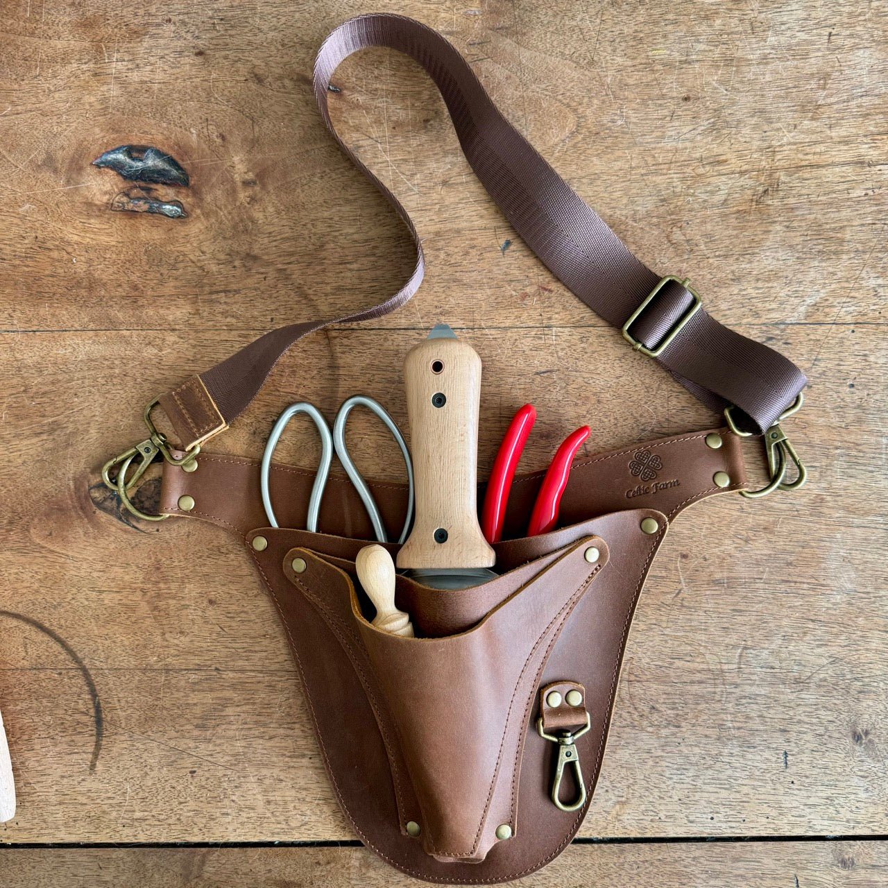 The Celtic Farm leather garden tool belt with extra rivet reinforcement, designed for master gardeners, shown with multiple tool holders.