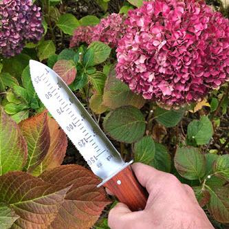 The Celtic Farm Hori Hori gardening tool in a gift box, featuring a sharp blade and wooden handle for planting and digging tasks.