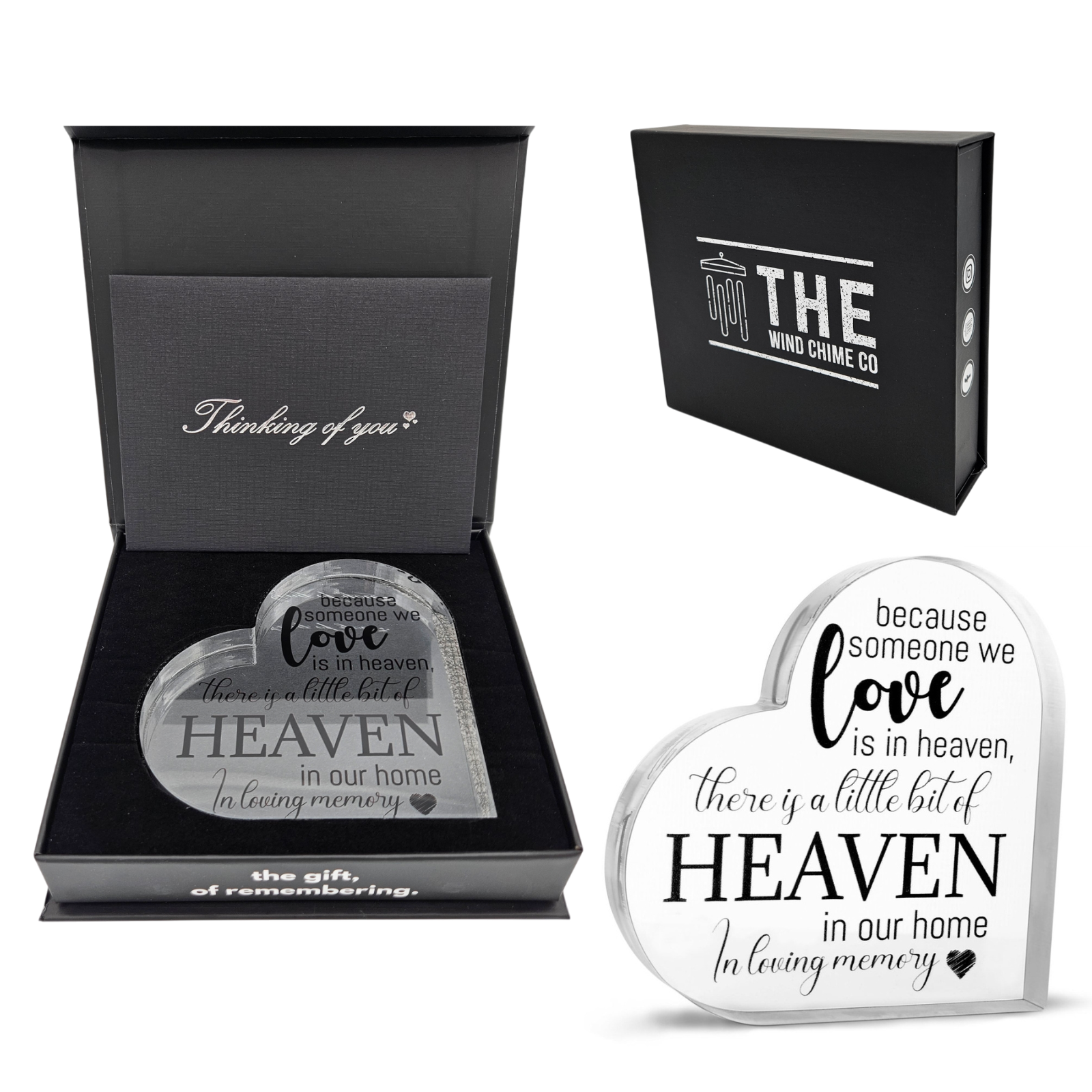 Acrylic memorial heart ornament with "Heaven In Our Home" inscription, designed by The Wind Chime Co, resting on a wooden surface.
