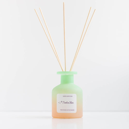Reed diffuser labeled "The Wind of Summer" by Timeless Organics Skin Care, featuring a glass container with reeds and a floral design.