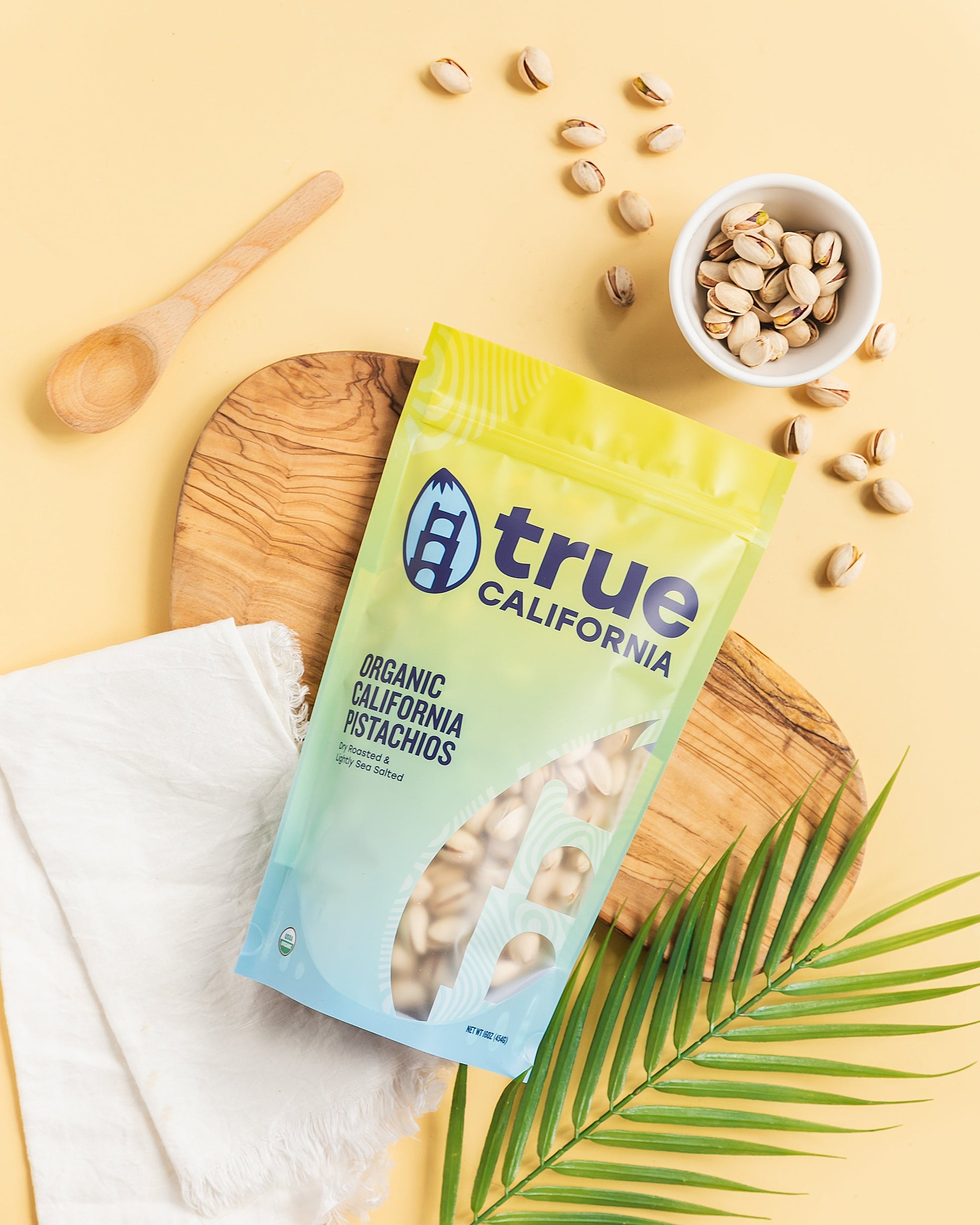 Organic True California pistachios, dry roasted and lightly salted, in a 1 lb package, displayed in a clear bowl.