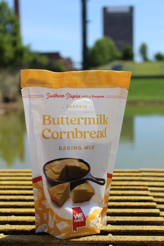 Box of WE Made Buttermilk Cornbread Mix with prepared cornbread slices on a plate