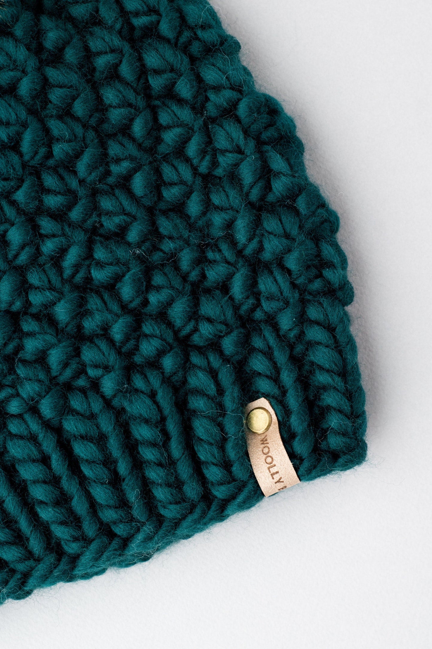 Forest green Peruvian wool knit hat with faux fur pom-pom by Woolly Bear Knits, cozy and stylish winter accessory.