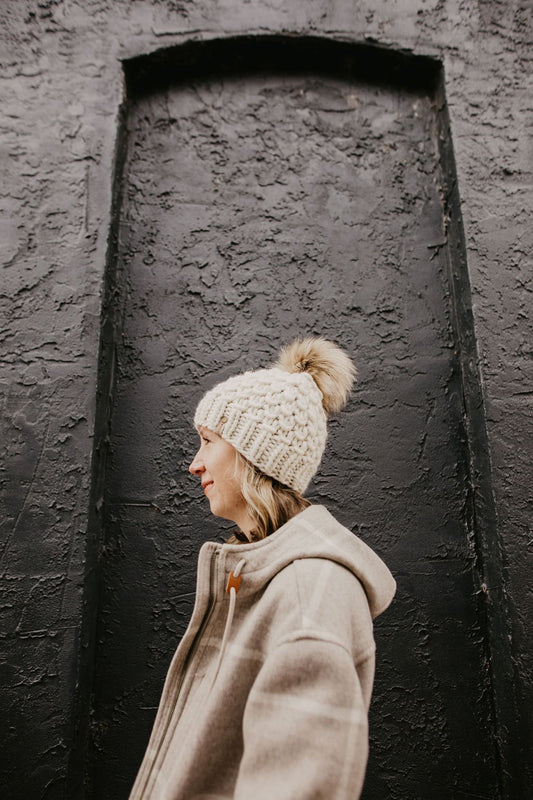 Ivory Peruvian wool knit hat by Woolly Bear Knits with a fluffy faux fur pom-pom on top.