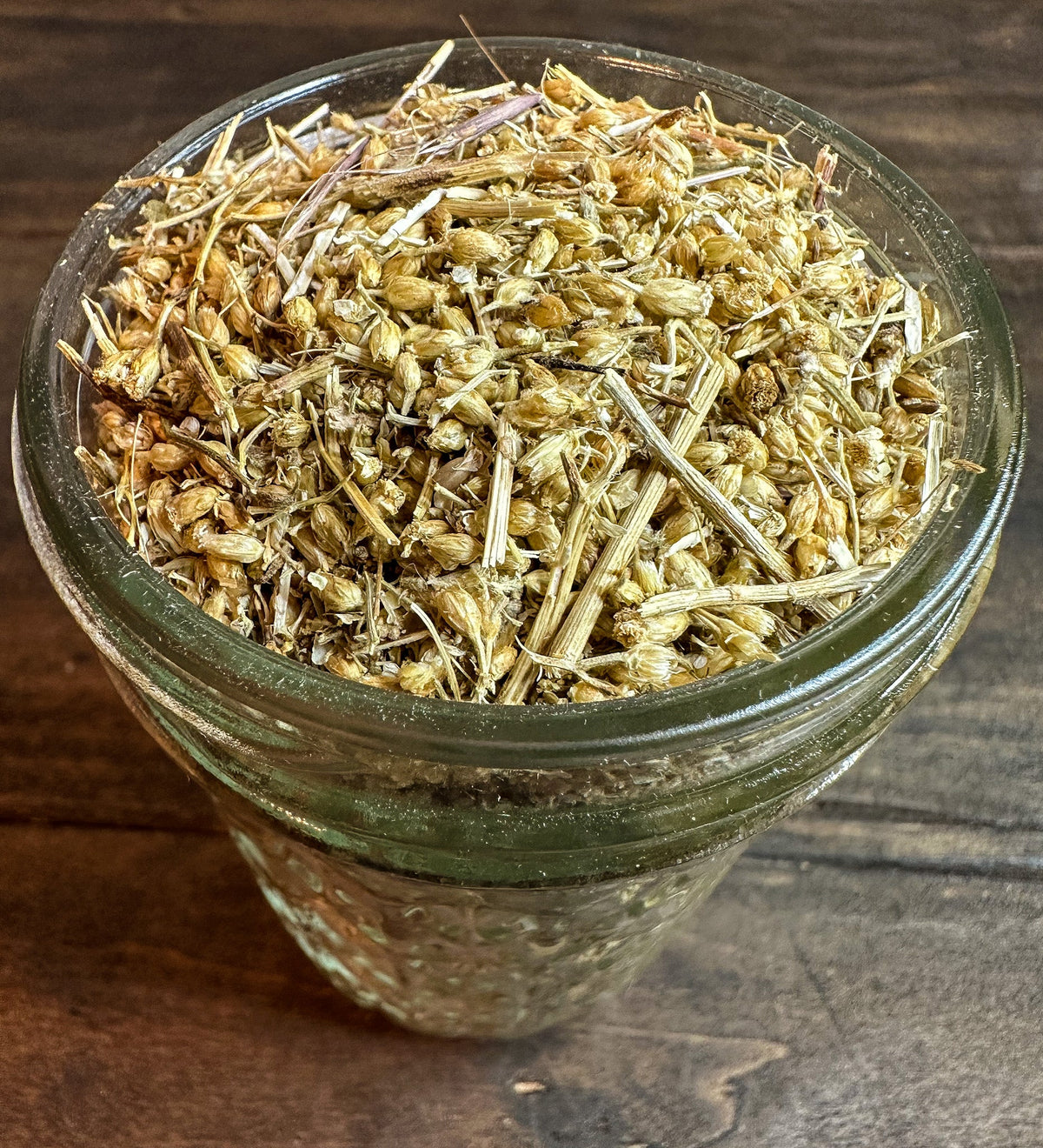 Small jar of dried yarrow herbs in herbalroseapothecary herb jar, showing the herbal contents and jar label.