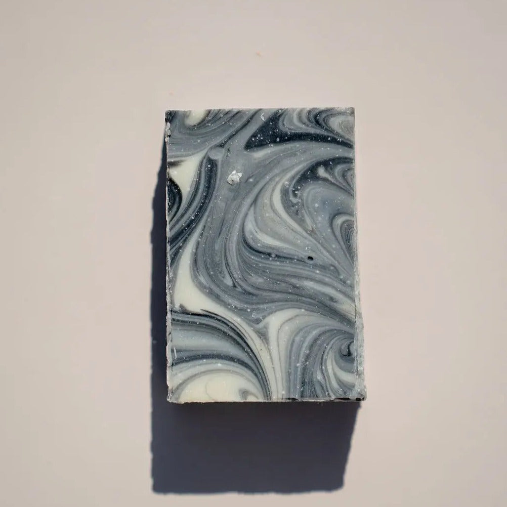 Bar of Farmer Tom's Soap by Your Only Earth with natural ingredients, shown in a rustic setting.