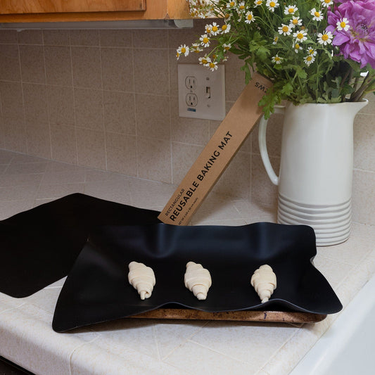 Two silicone baking mats on a baking sheet, non-stick, flexible, and reusable, perfect for baking and roasting.