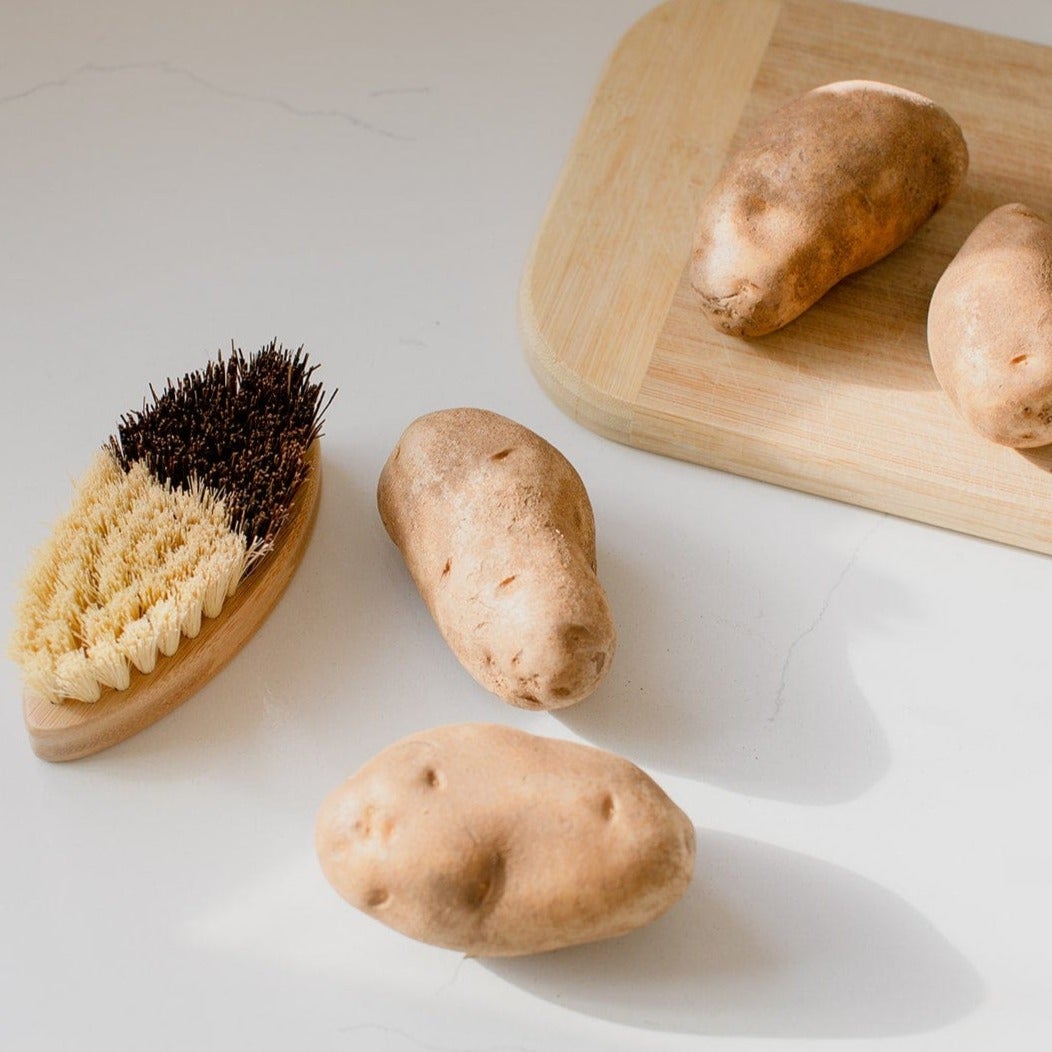 Vegetable scrub brush from ZeroWasteStore.com with a wooden handle and bristles for cleaning produce effectively.